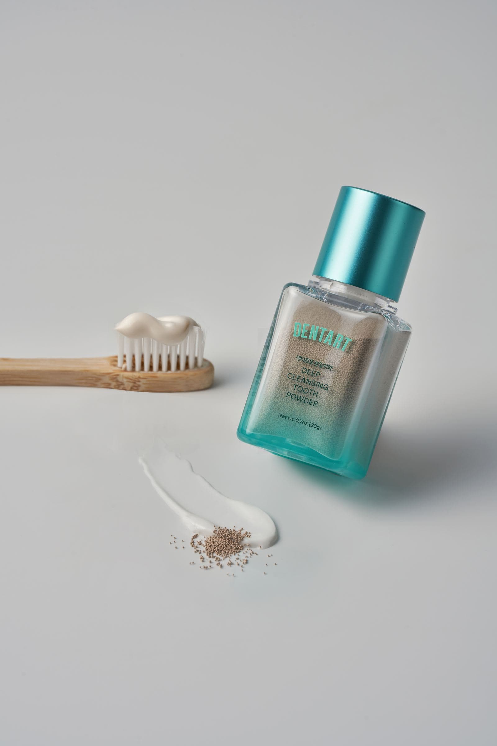 Bamboo toothbrush with toothpaste beside Dentart powder